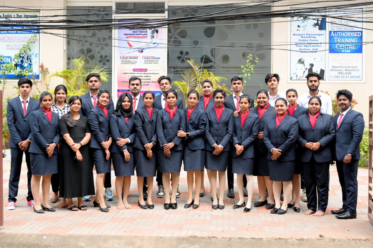 Full batch of Airline Institute students in navy aviation uniform with red scarves and ties outside the Trivandrum training centre